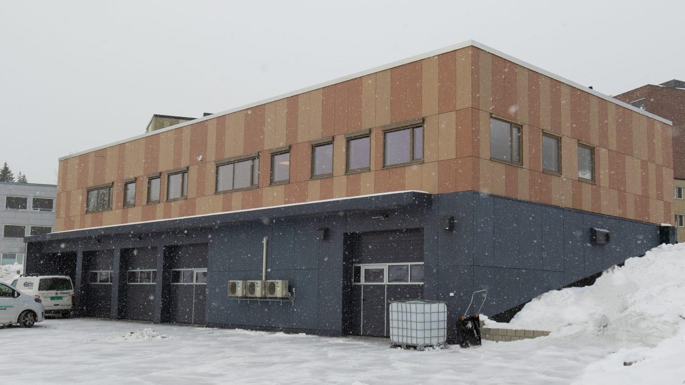 The ambulance station at Helgelandssykehuset, a two-storey building clad in timber and dark panels, with garage doors on the ground floor